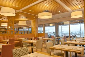 Innenansicht des Restaurants im Seth 55 Santo Tomás Hotel mit holzvertäfelter Decke und großen Fenstern.