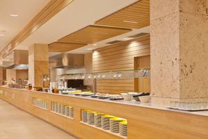 Buffetbereich des Seth 55 Santo Tomás Hotels mit Holzsäulen und einer Glastheke voller Speisen.