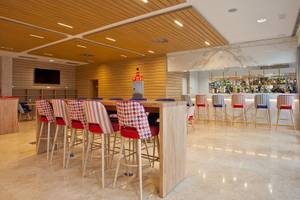 Innenbereich der Bar im Seth 55 Santo Tomás Hotel mit Holztischen, farbenfrohen Stühlen und einer Bar im Hintergrund.