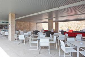 Innenlounge des Seth 55 Santo Tomás Hotels mit weißen Tischen und Stühlen und einem roten Sofa.