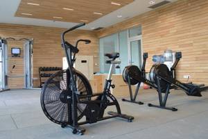 Fitnessstudio im Seth 55 Santo Tomás Hotel mit verschiedenen Trainingsgeräten und Holzwänden.