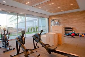 Fitnessraum im Hotel Seth 55 Santo Tomás mit Geräten und großen Fenstern.