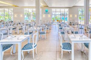 Innenansicht des Buffet-Restaurants im Senator Puerto Plata Spa Resort mit weißen Tischen und Stühlen, Blick auf das Meer.