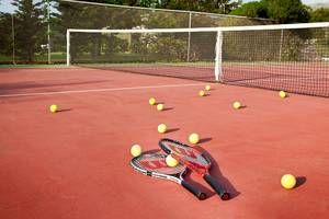 Tennisplatz mit Schlägern und Bällen, alles bereit für ein Spiel.