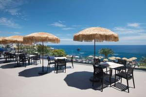 Außenterrasse des Baia Azul Hotels mit Blick auf das Meer und Palmen.