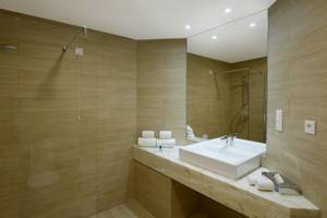 Badezimmer im Baia Azul Hotel mit einer Dusche, Waschbecken und Handtüchern.
