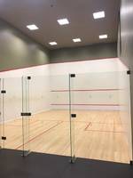 Leerer Squashplatz im Saccharum Hotel mit Glaswänden und hölzernem Boden.