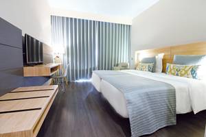 Doppelzimmer im Madeira Panorâmico Hotel mit zwei Betten, Fernseher, Schreibtisch und Vorhängen.