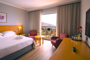 Hotelzimmer mit komfortablem Bett, Möbeln und Terrasse mit Blick auf den Berg