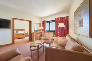 Innenansicht der Suite im Hotel Porto Mare - PortoBay mit Wohnzimmer, Schlafbereich und Blick auf den Ozean.