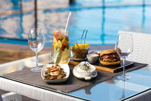 Eine Terrasse mit Getränken und Essen vor einem Pool, The Views Oasis Hotel