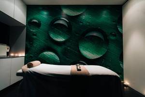 Massageraum im Views Oasis Hotel mit grünem Blattmuster und Wassertropfen auf der Wand.