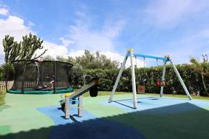 Kinderspielplatz im Freien im The Views Oasis Hotel mit Trampolin, Schaukel und Rutsche.