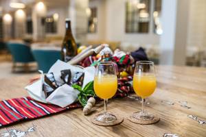 Frühstückstisch im Views Oasis Hotel mit zwei Gläsern Orangensaft und einem Korb mit Gebäck.