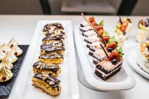 Eine Auswahl an Desserts auf einem Buffet im Views Oasis Hotel, darunter Schokoladencreme-Eclairs, Mini-Kuchen und Meringues.