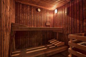 Innenansicht einer Sauna mit Holzwänden, Bänken und einer Uhr an der Wand im Views Oasis Hotel.