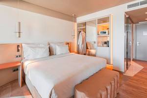 Ein modernes Hotelzimmer von The Views Baia mit großem Bett, weißen Kissen und Holzboden.