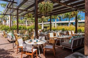 Außenbereich des Savoy Palace Gartenrestaurants mit Holzböden und hängenden Pflanzen.