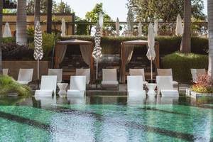 Pool-Lounge-Bereich im Savoy Palace Hotel mit weißen Liegestühlen und Sonnenschirmen.