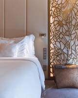 Schlafzimmer im Savoy Palast Hotel mit weißem Bett und goldenem Wandpaneel