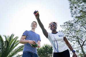 Zwei Personen, eine Frau und ein Mann, spielen mit bunten magischen Würfeln in einem Garten.