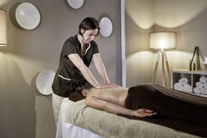 Eine Frau im schwarzen Outfit führt eine Massage in einem Raum des Falesia Hotels im Algarve durch.