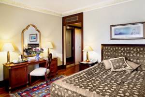 Schlafzimmer im Eresin Sultanahmet Hotel mit Bett, Nachttischen, Stühlen und Blumenvase.