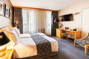Hotelzimmer von Les Jardins du Marais mit zwei Betten, Schreibtisch und Fernseher.