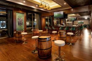 Innenansicht der Bar im Rixos Premium Belek Hotel mit hölzernem Boden und grünen Stühlen.