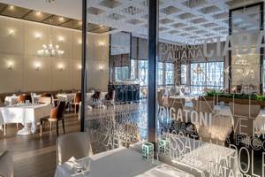 Innenansicht des Restaurants im Rixos Premium Belek mit Tisch, Stühlen und Glaswänden.
