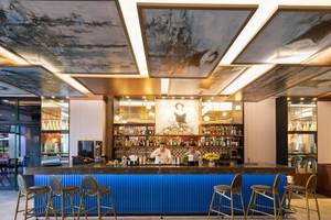 Innenansicht der Bar im Rixos Premium Belek Hotel mit Barkeepern und Kunden.