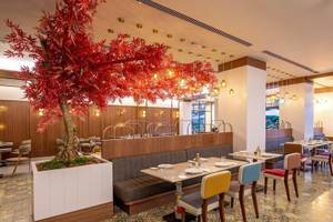 Innenansicht des Rixos Premium Belek Restaurants mit Tisch, Stühlen und rotem Baum