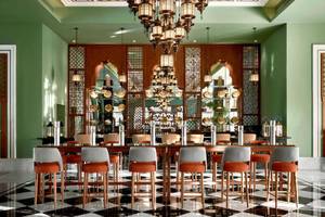 Speisesaal im Steigenberger Resort Alaya mit grünen Wänden, schwarzen und weißen Bodenfliesen, und einer großen Holztisch mit Barhockern.