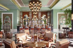 Lobby des Steigenberger Resort Alaya mit einer großen Kronleuchter, Holzstühlen und Tischen.