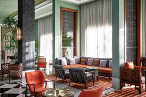 Ein modernes Hotellobby mit Sitzbereich, Sofas, Sesseln, Tisch, Teppich, und Pflanzen.