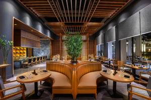 Innenansicht des Restaurants im Steigenberger Resort Alaya mit braunen Möbeln und einer großen Pflanze.