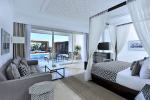 Hotelzimmer mit Bett, Sofa und Blick auf den Pool im Steigenberger Resort Alaya.