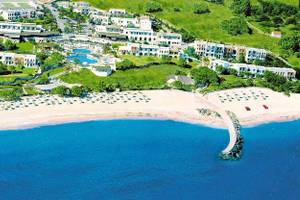 Außenansicht des Mitsis Cretan Village Resorts mit Pool, Strand und Gebäuden.