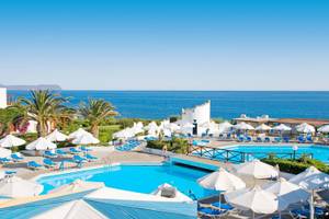 Außenbereich des Mitsis Cretan Village Resorts mit Swimmingpools, Sonnenliegen und Sonnenschirmen.