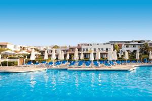 Außenpoolbereich des Mitsis Cretan Village Hotels mit weißen Liegestühlen und Sonnenschirmen