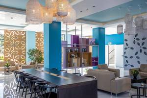 Innenbereich der Lobby im Asterias Beach Resort mit blauen Säulen, modernen Möbeln und dekorativen Leuchten.