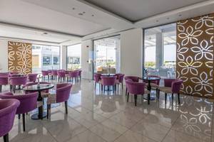 Innenbereich des Asterias Beach Resort mit violetten Stühlen und Tischen.