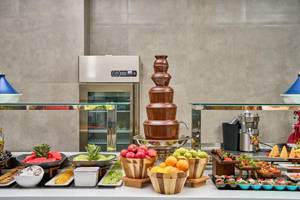 Buffet-Tisch im Lindos Grand Resort & Spa mit Schokoladenbrunnen, Obst und Desserts.