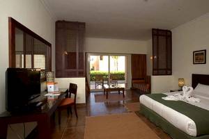 Gemma Resort Hotelzimmer mit Bett, Fernseher, Tisch und Balkonzugang.