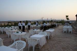 Terrasse des Mangrove Bay Resorts bei Sonnenuntergang mit aufgestellten Tischen und Stühlen.