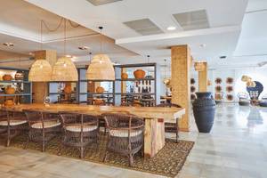 Speisebereich im Fergus Style Bahamas Hotel mit einem großen Holztisch und Rattanstühlen.