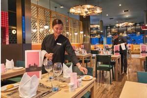 Ein Mitarbeiter des RIU Atoll Hotels bereitet einen Tisch in einem Restaurant vor.