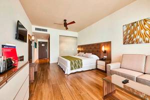 Innenansicht eines Hotelzimmers im RIU Atoll Hotel mit Bett, Couch, Fernseher und Schreibtisch.