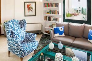 Wohnzimmer des Kalidon Panorama Hotels mit blauem Sessel, grauem Sofa und Bücherregal.