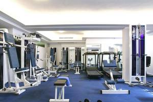 Fitnessstudio im Naxos Resort Beach Hotel mit verschiedenen Trainingsgeräten und einer blauen Trainingsfläche.